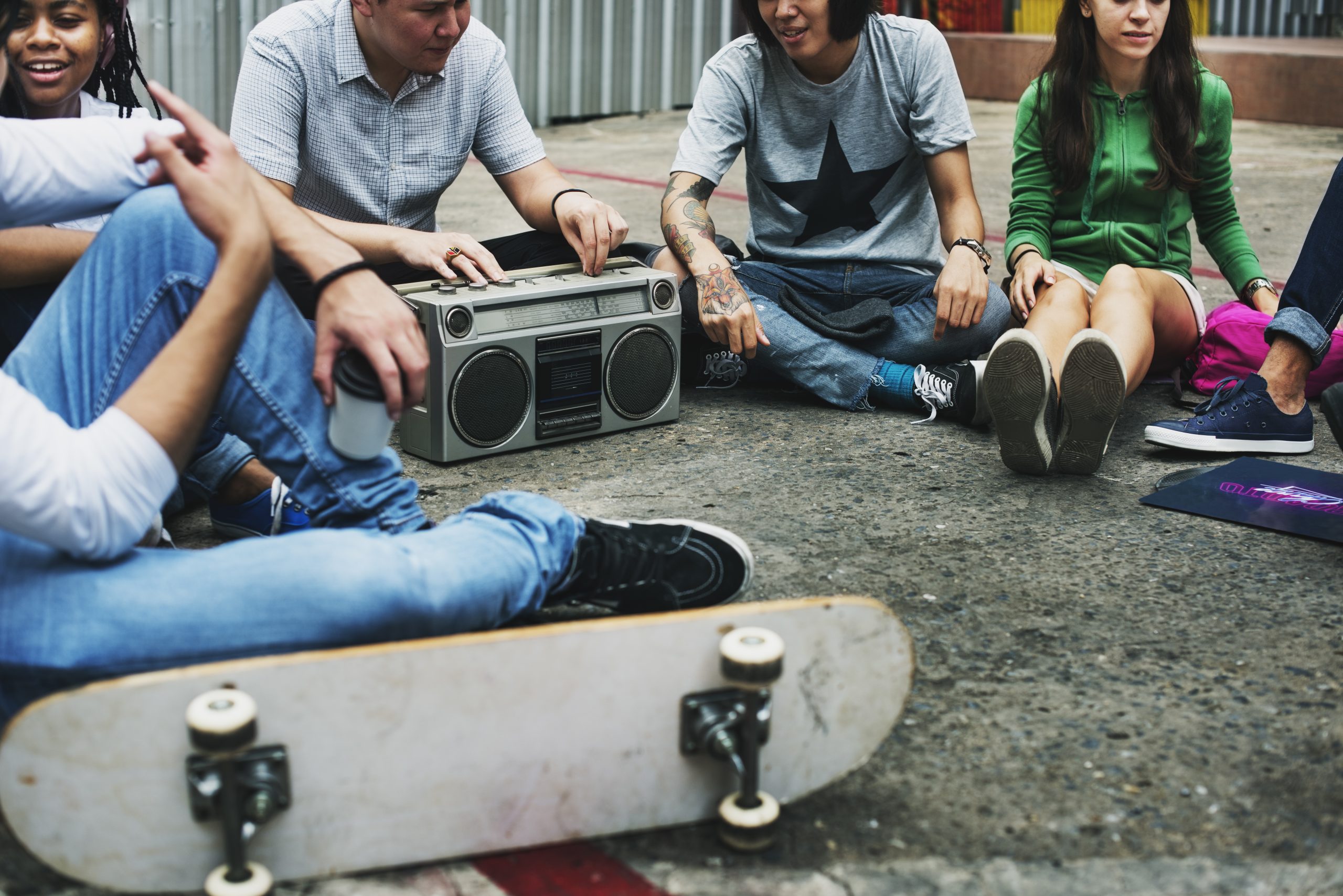 Ragazzi seduti in cerchio, boombox e skateboard